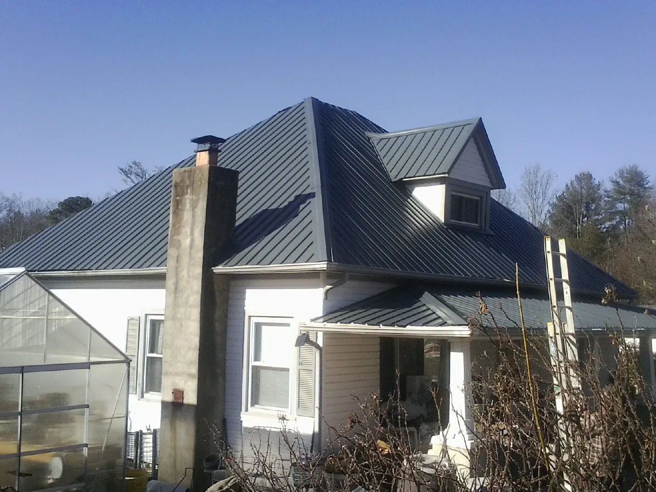 Dark blue standing seam metal roof on a white farmhouse with dormer — Slate & Tile Roof Repair by Roofing Brothers in Porter Corners