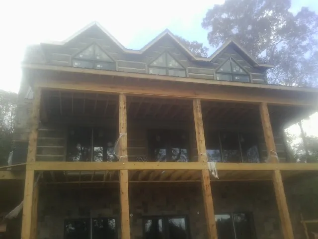 Dormers and porch framing on a large log home under construction — Roof Coating work by our crew in Porter Corners
