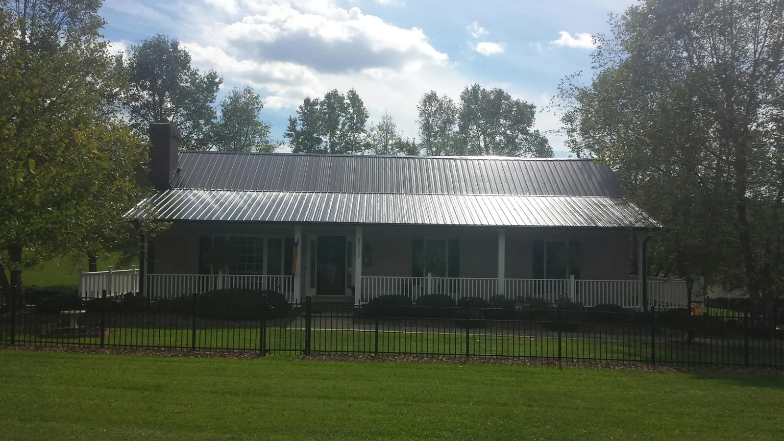 Gray metal roof on a brick ranch with a full width front porch — Gutter Guard Installation work by our crew in Porter Corners