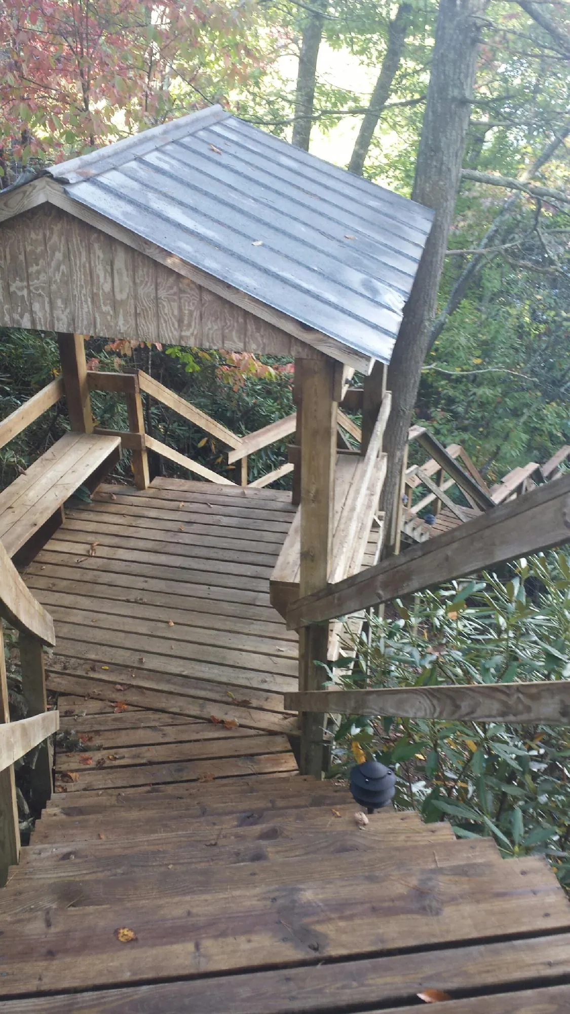 Metal roofed shelter over wooden steps on a wooded walkway — Skylight Repair & Installation work by our crew in Porter Corners