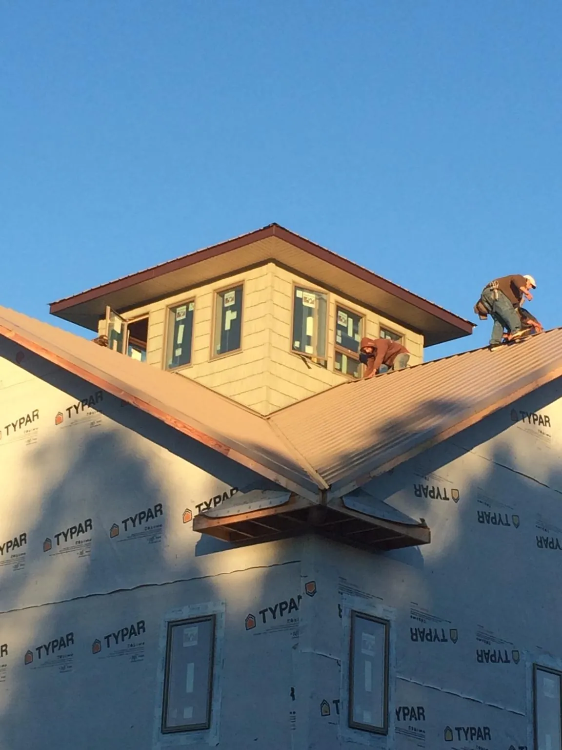 Roofers working around a rooftop cupola on a new metal roof at sunset — Roof Waterproofing in Porter Corners by Roofing Brothers